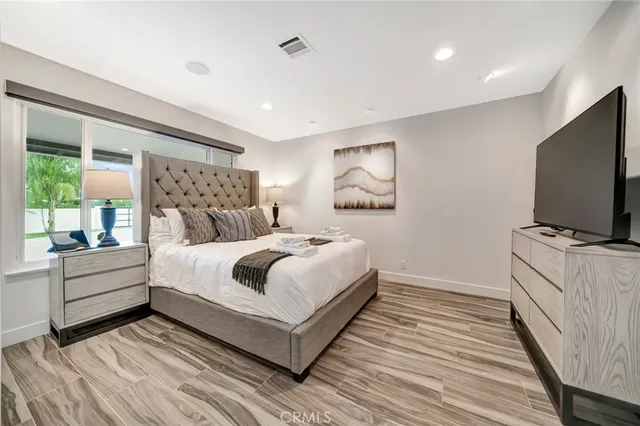 a bedroom with a bed a couch and a flat screen tv