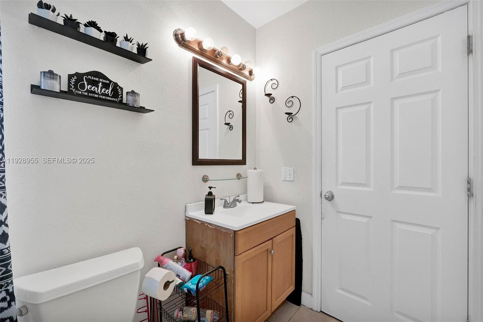 1910 Northwest 72nd Street Miami, FL 33147 - Photo 19 of 37 a bathroom with a toilet a sink and a mirror