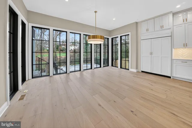 a view of an empty room with wooden floor and windows