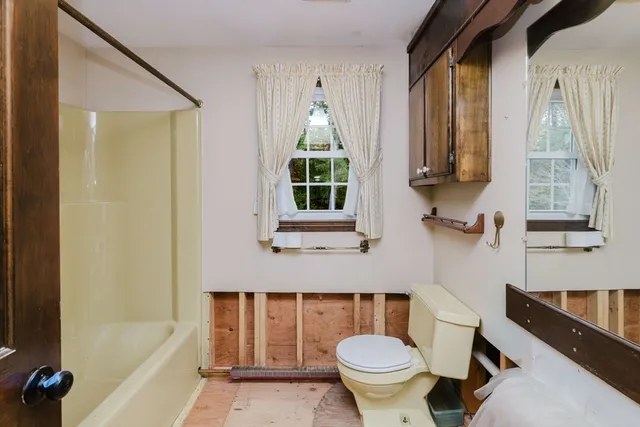 an empty room with ceiling fan and windows