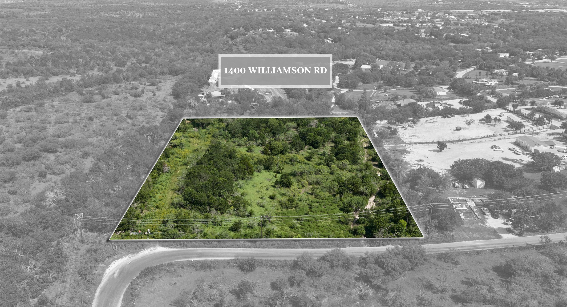 1400 Williamson Road Kyle, TX 78640 - Photo 2 of 13 A verdant, undeveloped lot nestled in a quiet, tree-filled rural setting.
