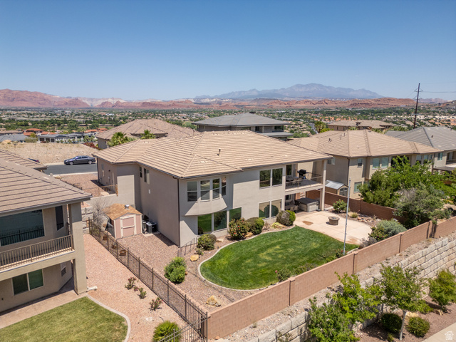 2005 West 450 S Circle St. George, UT 84770 - Photo 48 of 57 Rear exterior featuring a manicured lawn, paved patio area with a fire pit, and a fenced perimeter