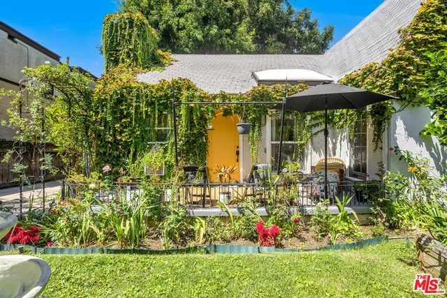a view of yellow house with a yard and sitting area