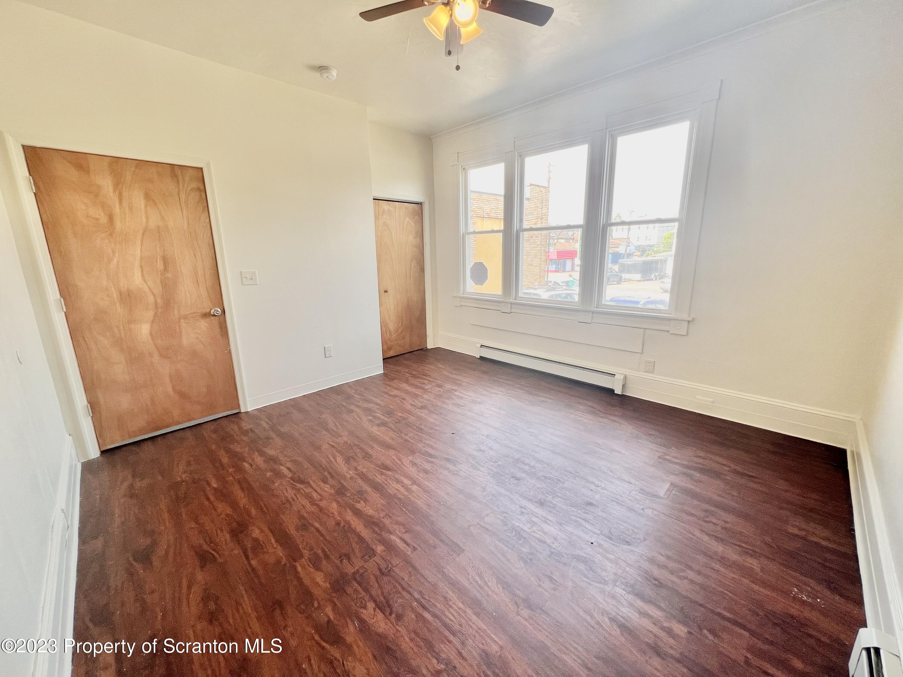 1930 Boulevard Avenue, Unit 1 Scranton, PA 18509 - Photo 8 of 9 an empty room with wooden floor chandelier fan and windows