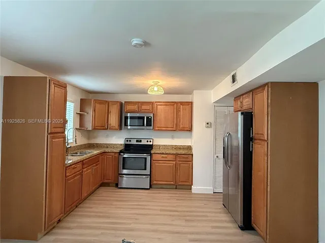 a kitchen with stainless steel appliances granite countertop a refrigerator and a stove top oven