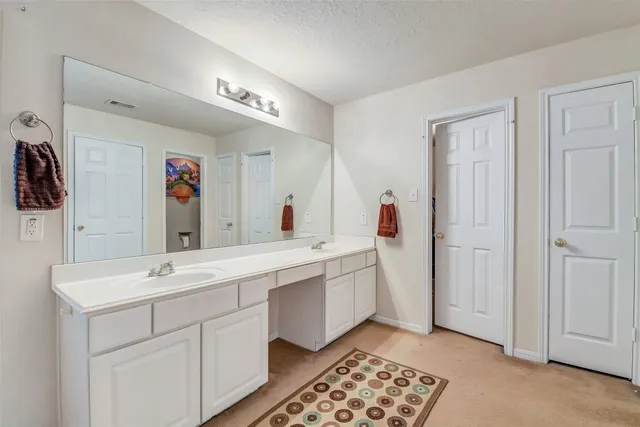 a spacious bathroom with a double vanity sink a mirror and a shower