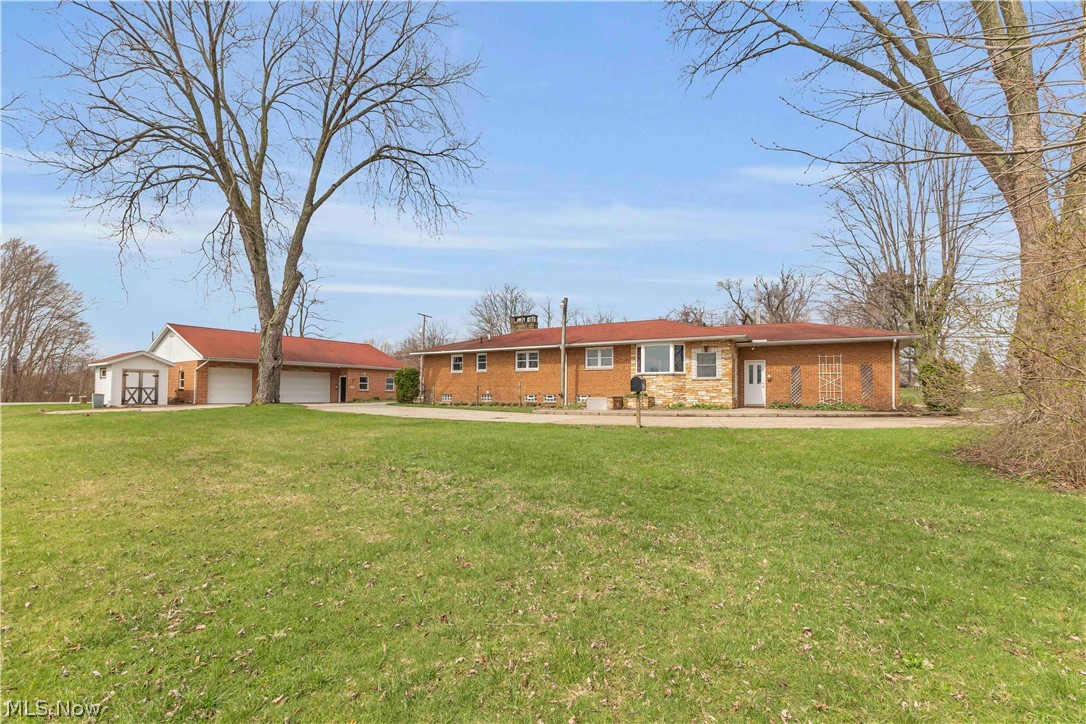 5500 North Ridge Road Madison, OH 44057 - Photo 2 of 49 Rear view of property featuring a yard, a chimney, an outbuilding, and driveway