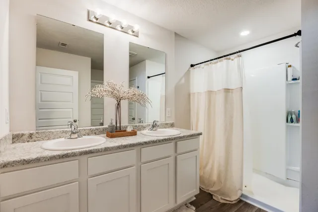 a bathroom with double vanity and a mirror