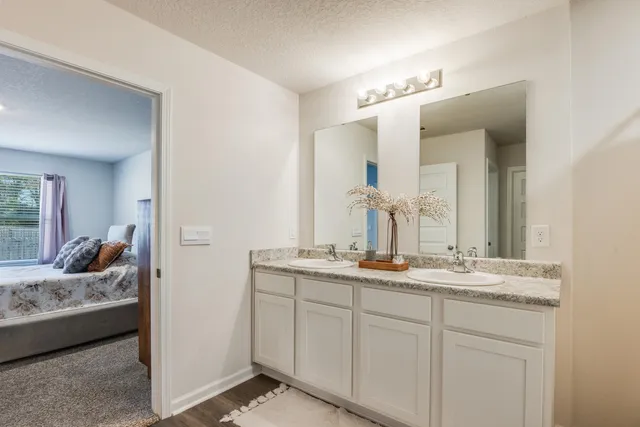 a en suite bathroom with a granite countertop sink and mirror