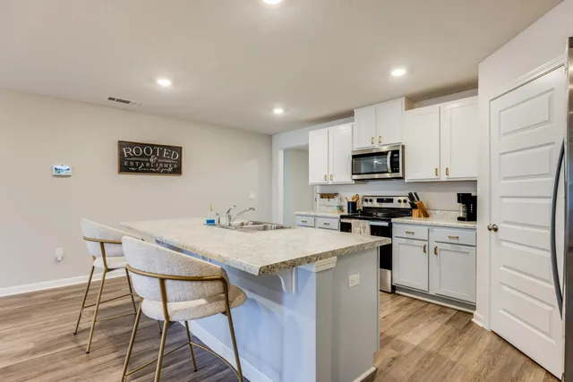 a kitchen with granite countertop white cabinets sink and stainless steel appliances