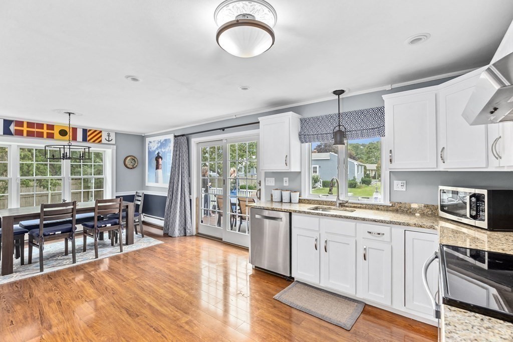 5 Atina Road Marshfield, MA 02050 - Photo 7 of 39 a open kitchen with stainless steel appliances granite countertop a stove top oven a sink a dining table and chairs with wooden floor
