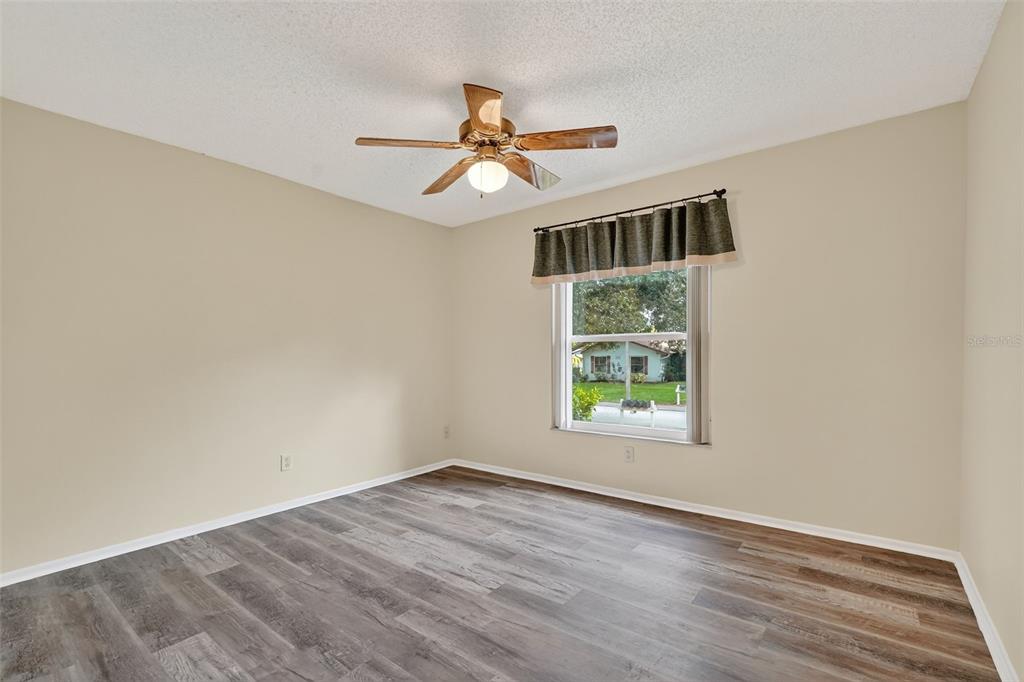 2320 Shelly Drive, Unit B Palm Harbor, FL 34684 - Photo 25 of 30 an empty room with wooden floor ceiling fan and windows
