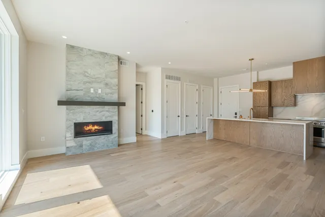 a view of kitchen and empty room with fireplace