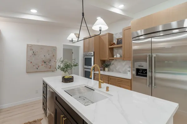 a kitchen with stainless steel appliances granite countertop a sink a refrigerator and a stove