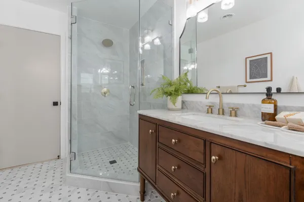 a bathroom with a granite countertop sink a mirror and shower