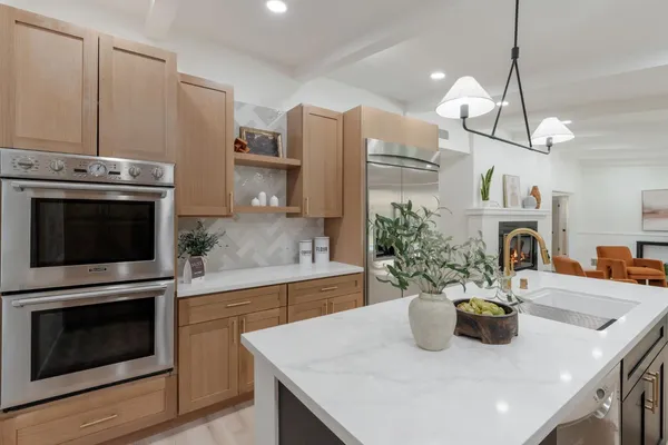 a kitchen with stainless steel appliances a stove a sink a microwave a refrigerator a stove and white cabinets