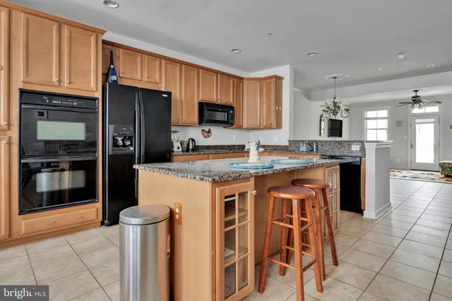 a kitchen with stainless steel appliances granite countertop a refrigerator a stove a sink a dining table and chairs