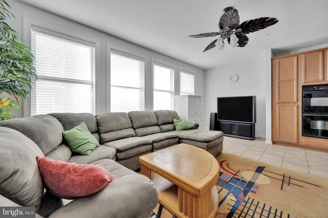 a living room with furniture a ceiling fan a flat screen tv and a large window