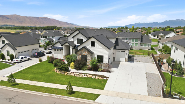 1002 West Temple Rim Lane Payson, UT 84651 - Photo 3 of 68 Contemporary two-story residence featuring a white siding and stone façade, black framed windows, and a dark shingle roof