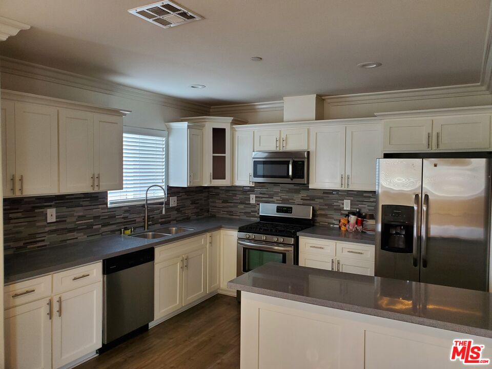 2227 Hauser Boulevard Los Angeles, CA 90016 - Photo 4 of 27 a kitchen with stainless steel appliances a sink stove microwave and refrigerator