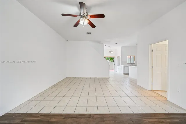 an empty room with wooden floor chandelier fan and windows
