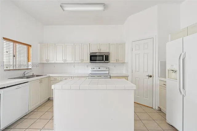a kitchen with a sink a stove a refrigerator and cabinets