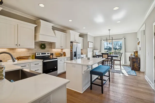 a kitchen with a sink a stove top oven and white cabinets