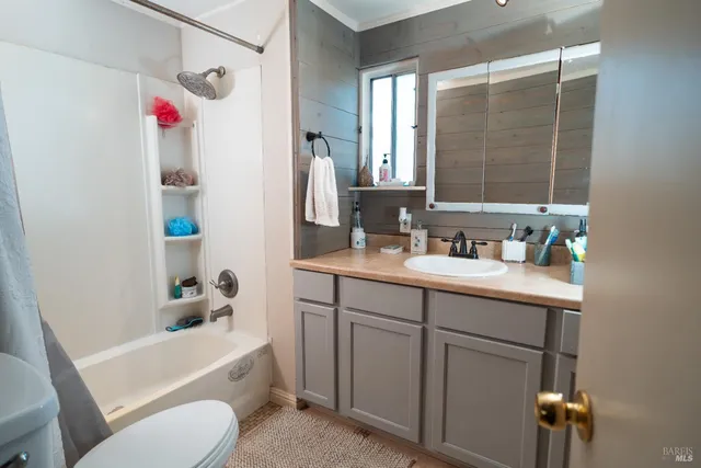 a bathroom with a sink vanity mirror bathtub shower and toilet