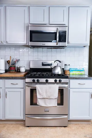 a kitchen with stainless steel appliances granite countertop white cabinets a stove a oven and microwave