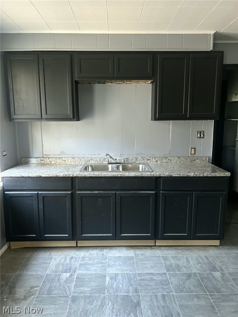 1069 Carlyon Road East Cleveland, OH 44112 - Photo 5 of 25 Black cabinetry with a double basin sink, light-toned countertop, and tiled flooring