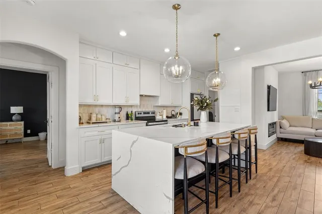 a kitchen with stainless steel appliances kitchen island granite countertop a stove a sink a dining table and chairs with wooden floor