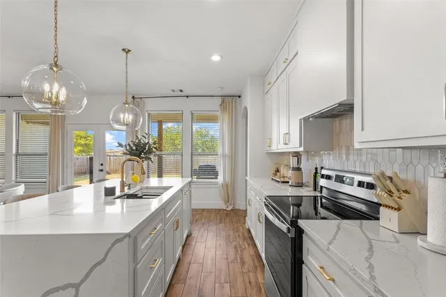 a kitchen with a sink stainless steel appliances a large window and cabinets