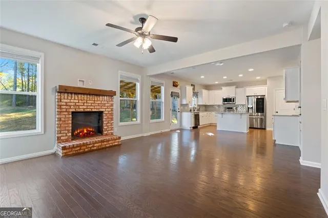 a view of an empty room with wooden floor and a kitchen