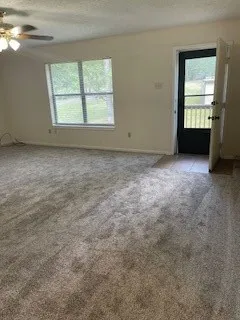 an empty room with a chandelier fan and windows