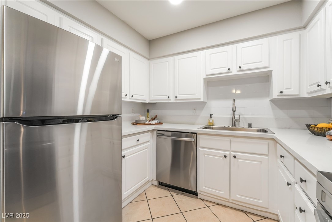 3151 North Soaring Gulls Drive, Unit 1083 Las Vegas, NV 89128 - Photo 12 of 45 Kitchen with appliances with stainless steel finishes, light countertops, white cabinetry, and light tile patterned floors