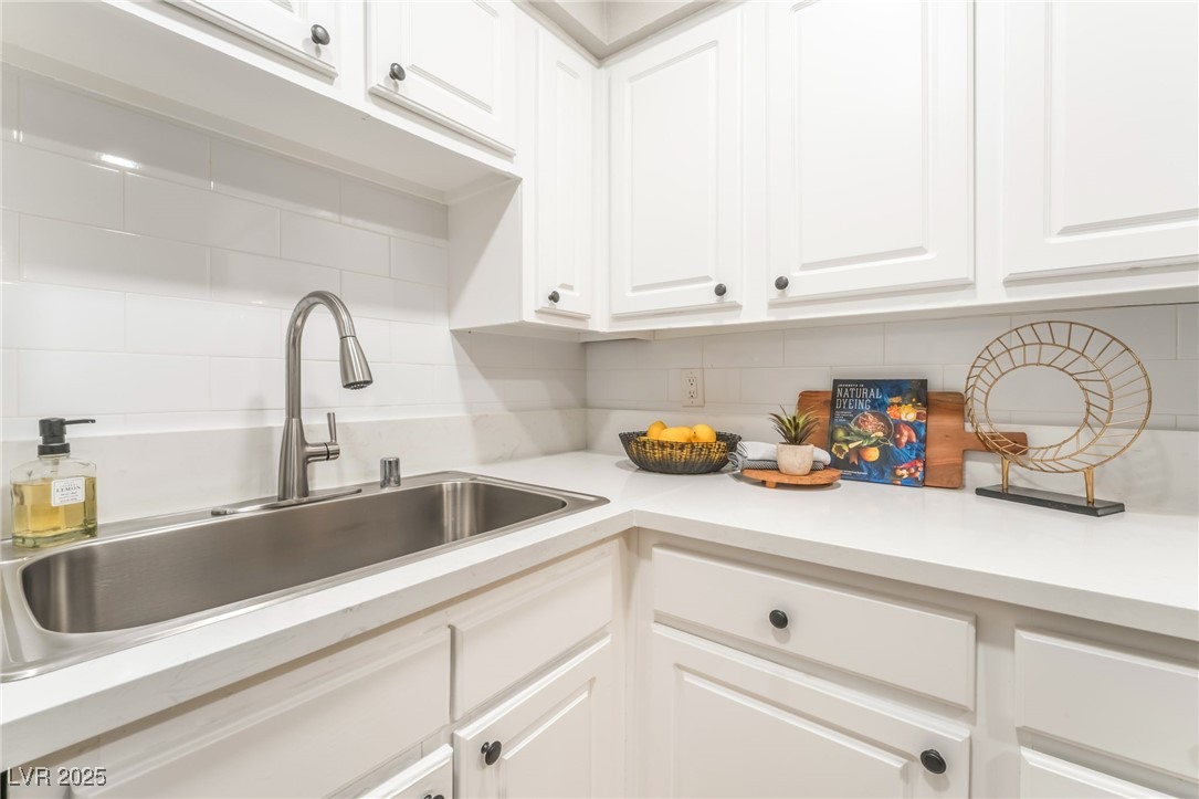 3151 North Soaring Gulls Drive, Unit 1083 Las Vegas, NV 89128 - Photo 13 of 45 Kitchen featuring white cabinetry, light countertops, and tasteful backsplash