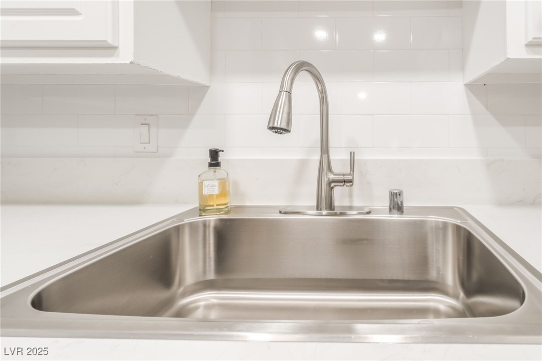 3151 North Soaring Gulls Drive, Unit 1083 Las Vegas, NV 89128 - Photo 15 of 45 Kitchen view of light countertops, white cabinetry, and decorative backsplash