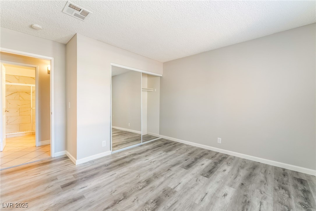 3151 North Soaring Gulls Drive, Unit 1083 Las Vegas, NV 89128 - Photo 21 of 45 Unfurnished bedroom featuring a textured ceiling, a closet, and wood finished floors