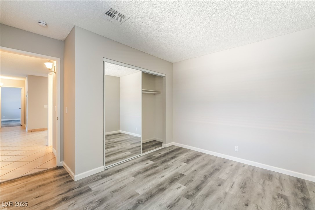 3151 North Soaring Gulls Drive, Unit 1083 Las Vegas, NV 89128 - Photo 25 of 45 Unfurnished bedroom with a textured ceiling, light wood finished floors, and a closet