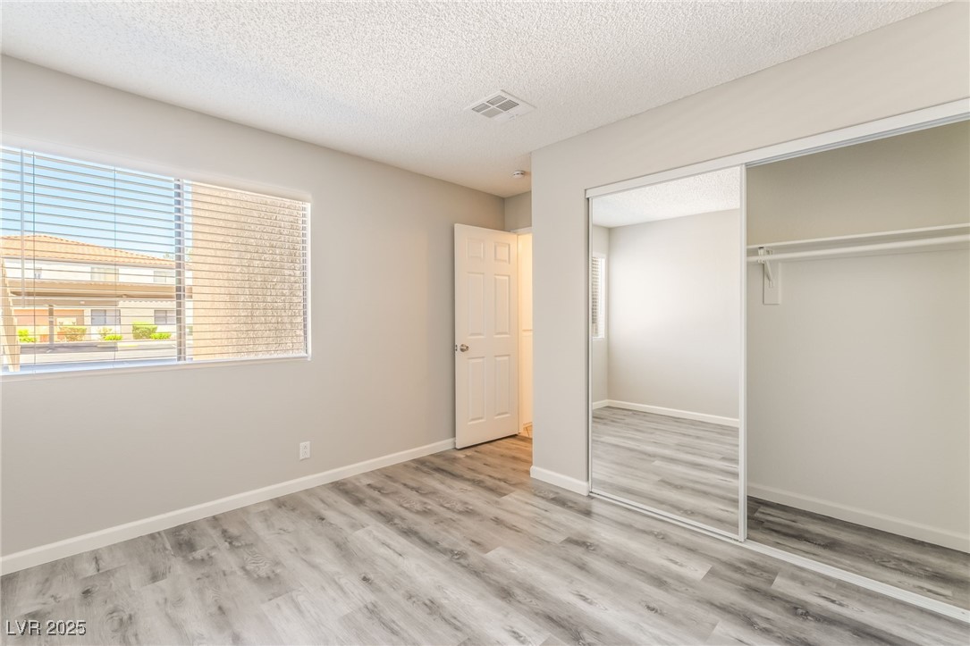 3151 North Soaring Gulls Drive, Unit 1083 Las Vegas, NV 89128 - Photo 26 of 45 Unfurnished bedroom featuring a textured ceiling, wood finished floors, and a closet