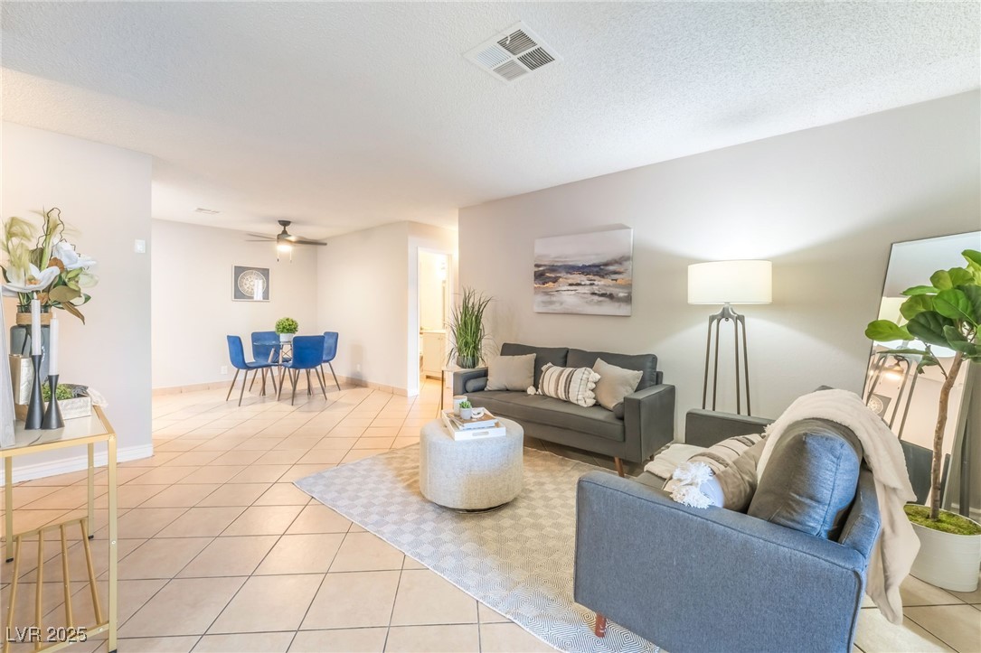3151 North Soaring Gulls Drive, Unit 1083 Las Vegas, NV 89128 - Photo 5 of 45 Living room featuring light tile patterned flooring, a ceiling fan, and a textured ceiling