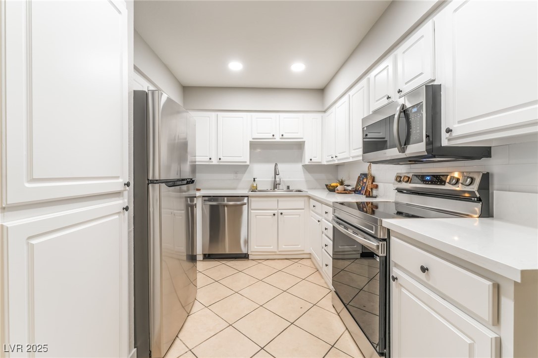 3151 North Soaring Gulls Drive, Unit 1083 Las Vegas, NV 89128 - Photo 10 of 45 Kitchen featuring stainless steel appliances, light tile patterned floors, light countertops, recessed lighting, and white cabinetry