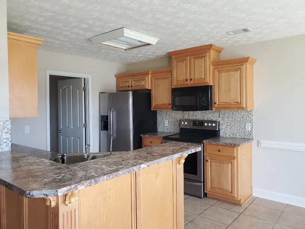 a kitchen with stainless steel appliances granite countertop a stove refrigerator and microwave
