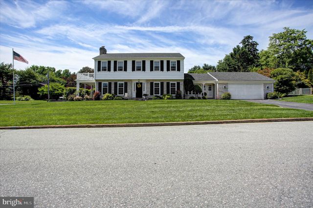a view of white house with a big yard and large trees