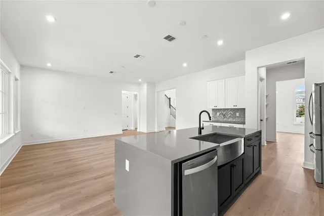 a kitchen with stainless steel appliances granite countertop a sink and a stove top oven with wooden floor