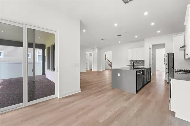 a large kitchen with stainless steel appliances kitchen island a large counter top and wooden floors