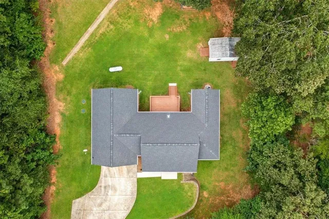 an aerial view of a house with a yard and trees all around