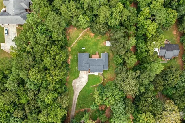 an aerial view of a house with a yard and trees all around