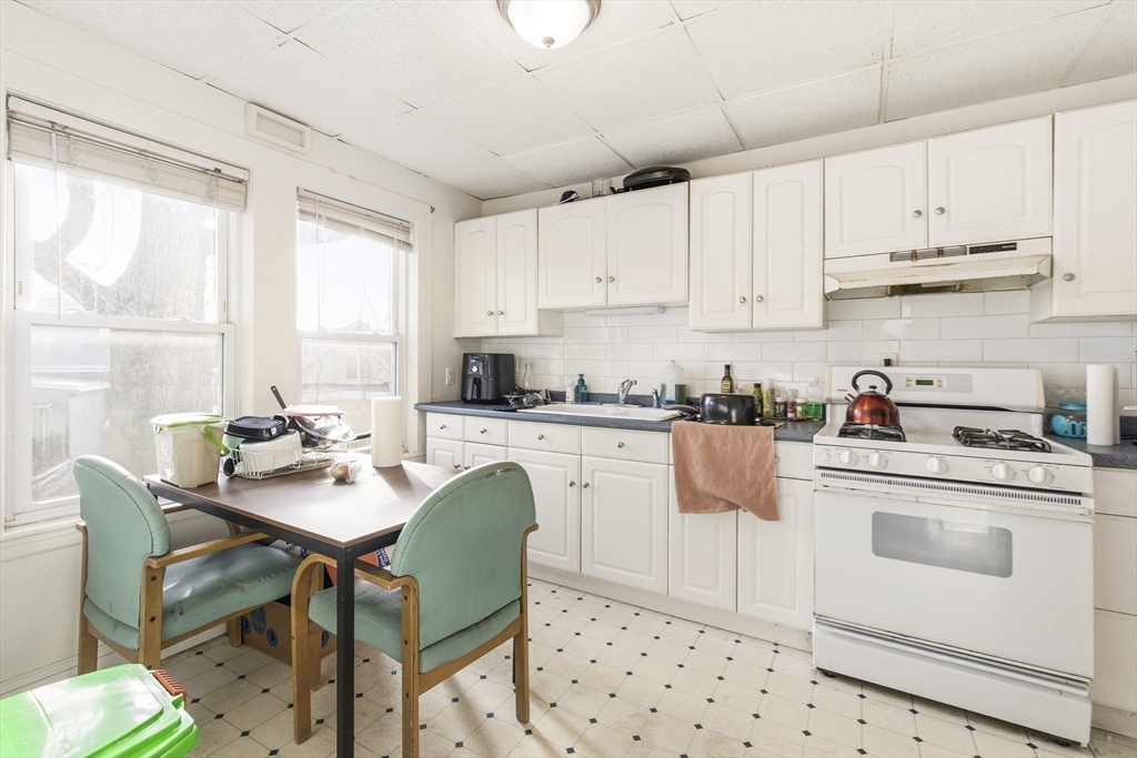 78 R Mt Vernon Street Somerville, MA 02145 - Photo 20 of 32 a kitchen with stainless steel appliances kitchen island granite countertop a table chairs and white cabinets
