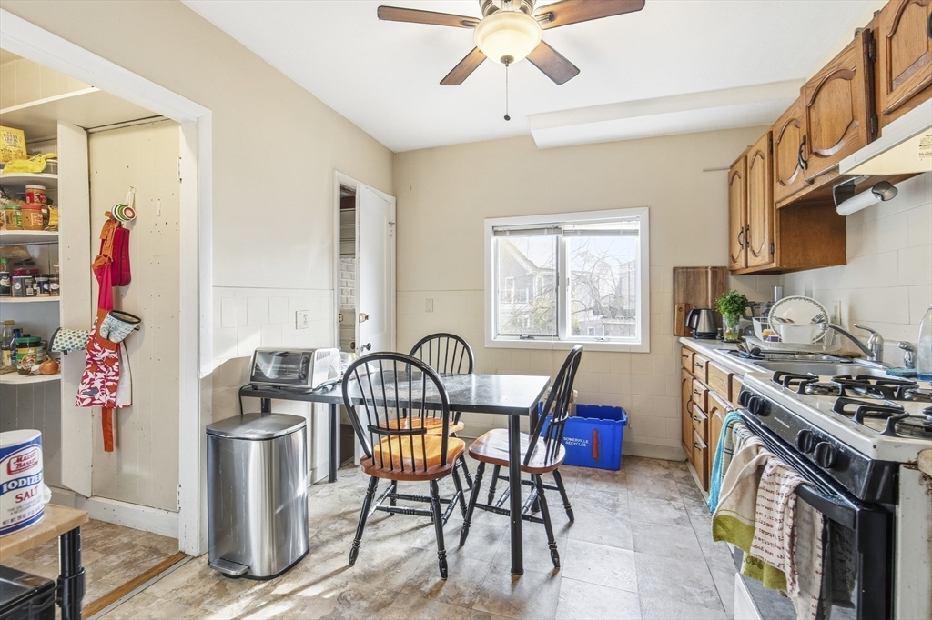 78 R Mt Vernon Street Somerville, MA 02145 - Photo 5 of 32 a kitchen with stainless steel appliances granite countertop a stove top oven a sink a dining table and chairs with wooden floor